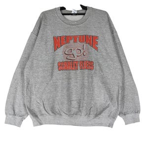 May include: A grey crew neck sweatshirt featuring the text "NEPTUNE GO! SCARLET FLIERS" in red. The sweatshirt has a classic, casual style, suitable for everyday wear. The fabric appears to be a soft, comfortable material.