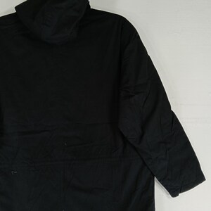 May include: A black hooded jacket with long sleeves. The jacket is made of a solid, dark fabric and features a hood. The garment is designed for outerwear and provides coverage for the upper body.