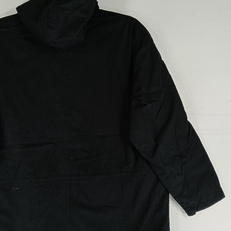 May include: A black hooded jacket with long sleeves. The jacket is made of a solid, dark fabric and features a hood. The garment is designed for outerwear and provides coverage for the upper body.