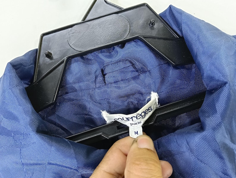 May include: A blue jacket with a white label that says "Mur&egrave;ges Paris" and "M" on it.