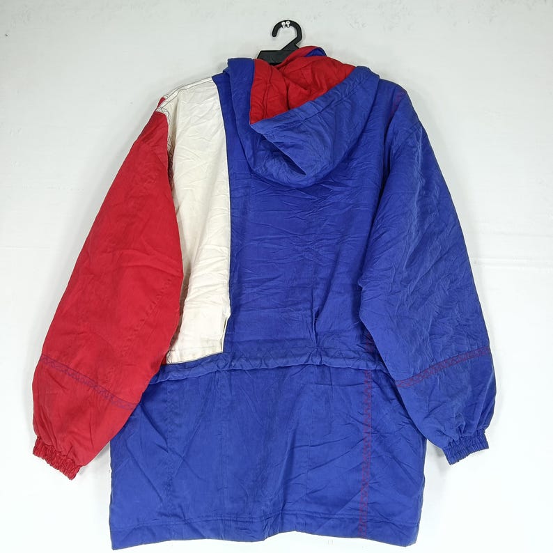 May include: A vintage hooded jacket in red, white, and blue color block design. The jacket has a full zipper, a hood, and elastic cuffs. The back of the jacket is visible, hanging from a black hanger.