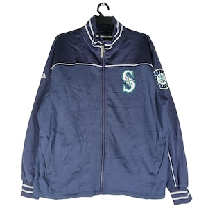 May include: Navy blue zip-up jacket with white and teal accents. Features the Seattle Mariners logo on the chest and a patch on the sleeve. The jacket has a stand-up collar and striped cuffs.
