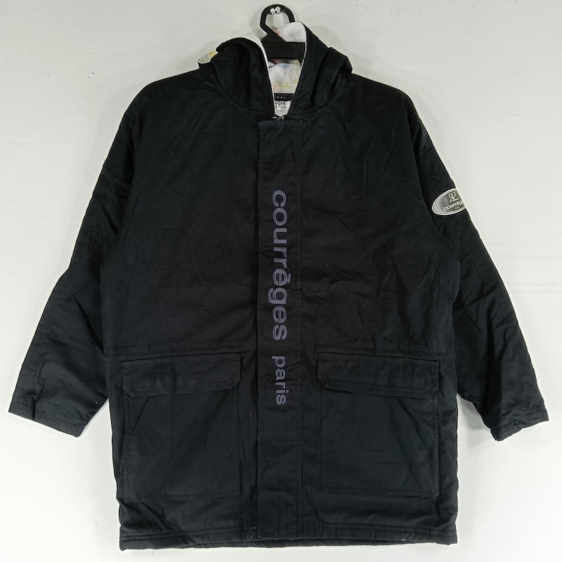 May include: Black hooded jacket with the text "courr&egrave;ges paris" vertically down the front. The jacket has two front pockets and a logo patch on the sleeve. The jacket is hanging on a white hanger.