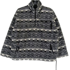 May include: A black, white, and gray fleece pullover with a high collar and a quarter-zip closure. The pullover features a patterned design with horizontal stripes and a small chest pocket. Two side pockets are also visible.