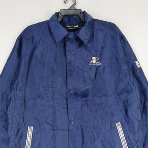 May include: A navy blue jacket with a button-up front and a white logo that says "Couragea" on the left chest. The jacket has two white zippered pockets on the bottom.