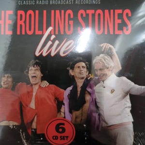 May include: A CD set of The Rolling Stones Live, featuring the band members in a live performance photo. The album cover is black with red text that reads "The Rolling Stones Live" and "6 CD SET".