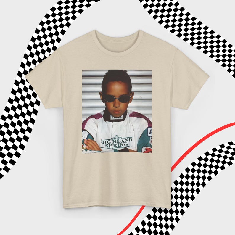 A sand t-shirt laid flat against a dynamic background of black-and-white checkered patterns and curved red lines. Centered on the shirt is a nostalgic photo print of a young Lewis Hamilton wearing sunglasses, arms crossed, and a vintage racing jacket with "Highland Spring" text. The brand name "VELORA" is displayed in the top-left corner in black, bold sans-serif font.