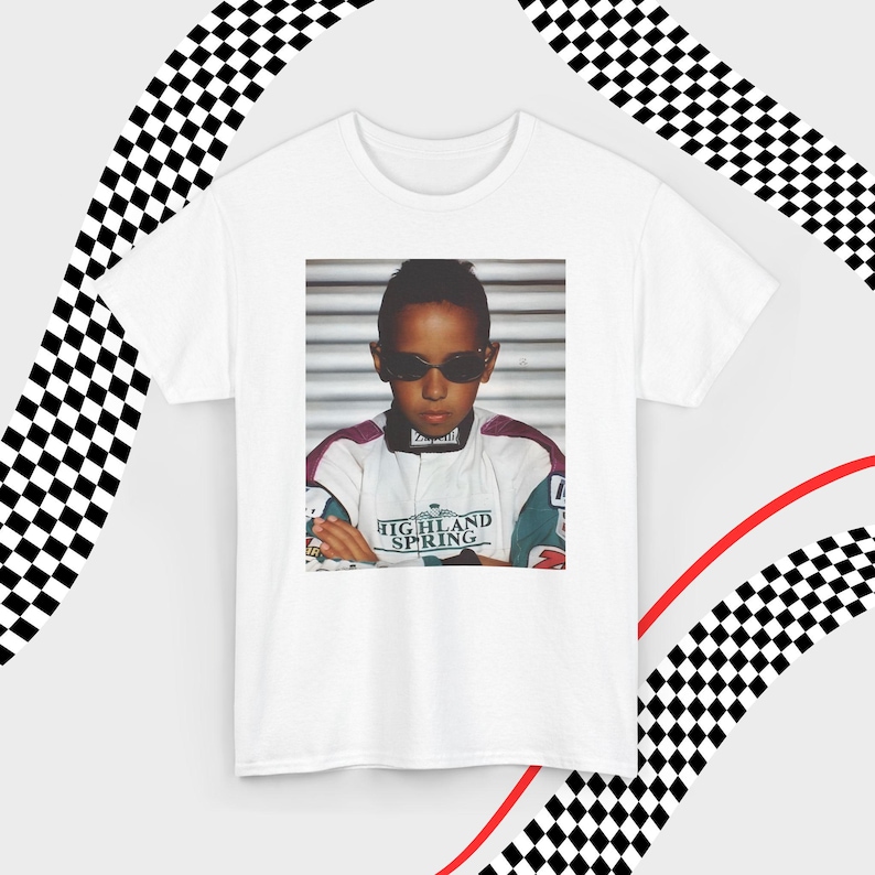 A white t-shirt laid flat against a dynamic background of black-and-white checkered patterns and curved red lines. Centered on the shirt is a nostalgic photo print of a young Lewis Hamilton wearing sunglasses, arms crossed, and a vintage racing jacket with "Highland Spring" text. The brand name "VELORA" is displayed in the top-left corner in black, bold sans-serif font.