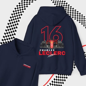 Puede incluir: Una sudadera con capucha azul marino con el n&uacute;mero 16 rojo y un coche de carreras rojo en la espalda. El texto "Charles Leclerc" est&aacute; impreso debajo del coche con una firma debajo. La parte delantera de la sudadera con capucha tiene un peque&ntilde;o logotipo bordado con el texto "Charles Leclerc".