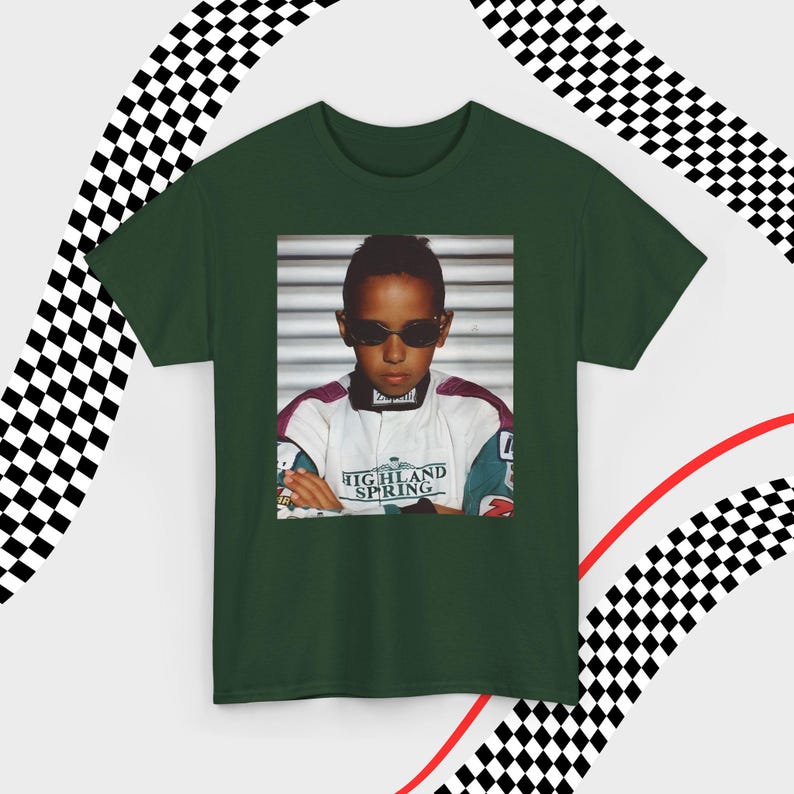 A green t-shirt laid flat against a dynamic background of black-and-white checkered patterns and curved red lines. Centered on the shirt is a nostalgic photo print of a young Lewis Hamilton wearing sunglasses, arms crossed, and a vintage racing jacket with "Highland Spring" text. The brand name "VELORA" is displayed in the top-left corner in black, bold sans-serif font.