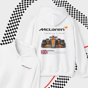 May include: White hooded sweatshirt with a McLaren Formula 1 Team logo, a racing car graphic, and the text "NORRIS" on the back. The front of the sweatshirt has a smaller McLaren logo.