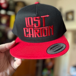 Embroidered Lost Carton Black/Red Snap Back Cap.