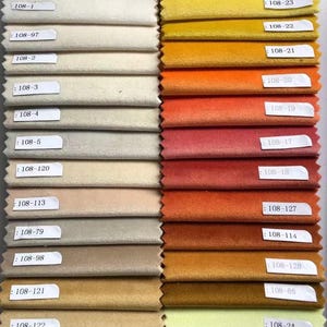 May include: A fabric swatch card featuring a variety of velvet samples in a range of colors. The swatches include shades of cream, beige, gold, orange, red, and green. Each swatch is labeled with a number.