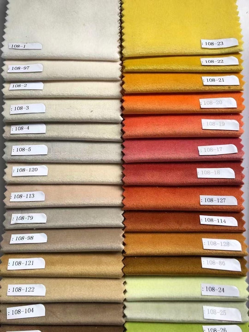 May include: A fabric swatch card featuring a variety of velvet samples in a range of colors. The swatches include shades of cream, beige, gold, orange, red, and green. Each swatch is labeled with a number.
