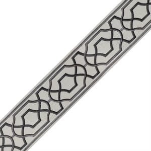 May include: A decorative trim with a repeating geometric pattern. The trim features a light gray background with a dark gray, stylized interlocking design. The edges are outlined in a darker gray, creating a defined border. This trim is suitable for various craft and design projects.