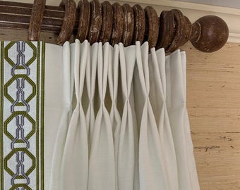 May include: White curtains with a green and gray geometric pattern border hanging from a wooden curtain rod.