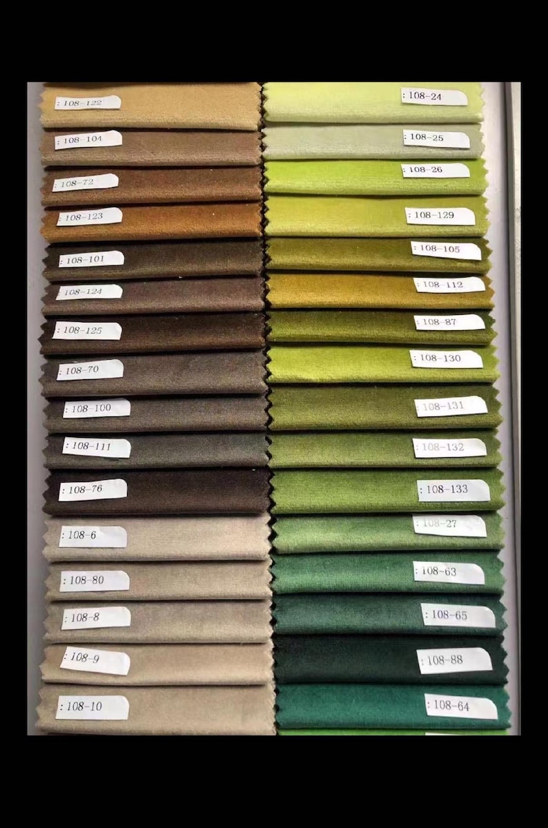 May include: A color swatch display featuring a variety of fabric samples in shades of green, brown, and beige. Each sample is labeled with a unique code, such as "108-24" and "108-122". The samples are arranged in neat rows, showcasing a range of textures and hues.