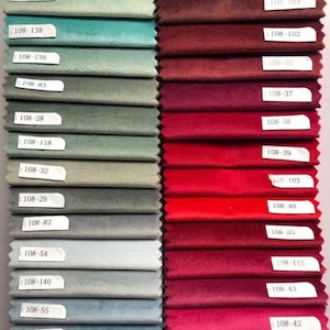 May include: A collection of fabric swatches in various colors, including shades of green, blue, red, and burgundy. Each swatch has a label with a number. The fabrics appear to be velvet or a similar plush material, ideal for upholstery or drapery.