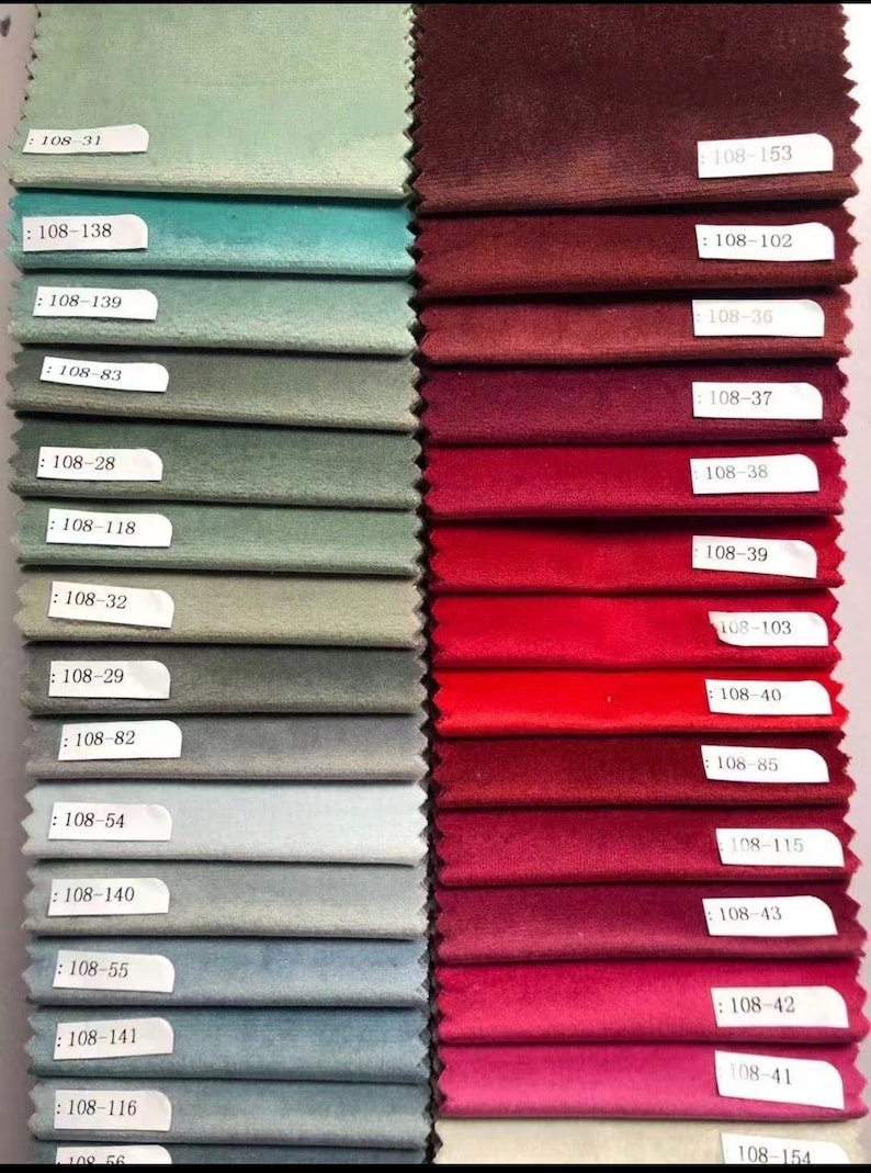 May include: A collection of fabric swatches in various colors, including shades of green, blue, red, and burgundy. Each swatch has a label with a number. The fabrics appear to be velvet or a similar plush material, ideal for upholstery or drapery.