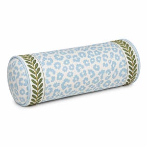 May include: A cylindrical bolster pillow featuring a light blue and white leopard print pattern on the main body, accented by light blue piping and a decorative border of green leaves on a white background at both circular ends of the pillow.