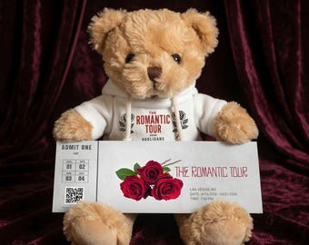 May include: A plush teddy bear wearing a white hoodie with "The Romantic Tour" text and holding a ticket. The ticket features red roses and event details: "The Romantic Tour" in Las Vegas, NV, from 4/10/2026 to 10/21/2026.