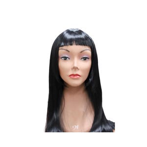 Puede incluir: Cabeza de maniquí con una peluca negra. La peluca presenta un flequillo recto y pelo largo y liso. El maniquí tiene tez clara, con maquillaje que incluye pintalabios rosa y sombra de ojos. El fondo es blanco.