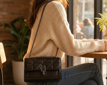 Peut inclure: Un sac à bandoulière noir matelassé de forme rectangulaire, doté d'un fermoir métallique et d'une fine chaîne. Le sac présente un design à rabat structuré avec un motif de surpiqûres en forme de grille sur toute la surface avant.