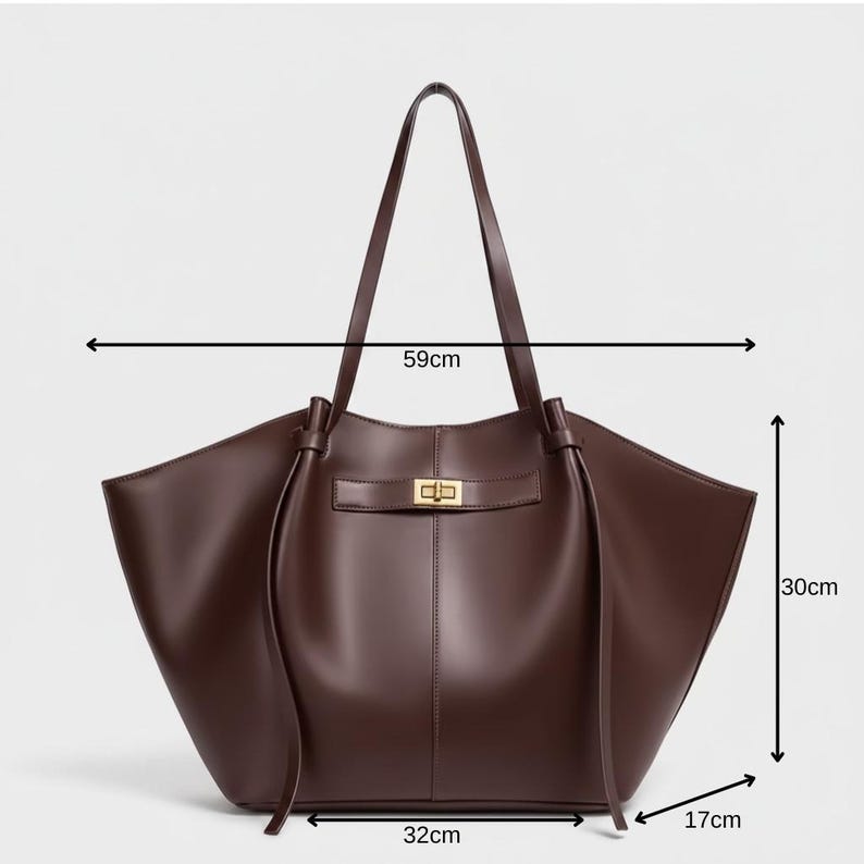 Puede incluir: Un bolso tote de cuero marr&oacute;n con forma rectangular. El bolso tiene un cierre dorado y dos asas largas. El bolso mide 59 cm de ancho, 30 cm de alto y 17 cm de profundidad.