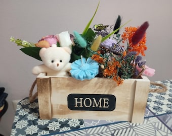 Scatola decorativa con candele profumate e fiori assortiti.