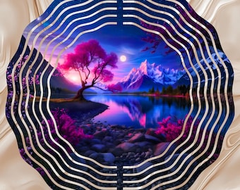 May include: A circular metal wind spinner featuring a vibrant landscape print of a moonlit lake, snow-capped mountains, and a prominent pink-leafed tree. The design includes concentric wavy cutouts that create a layered, dimensional effect.