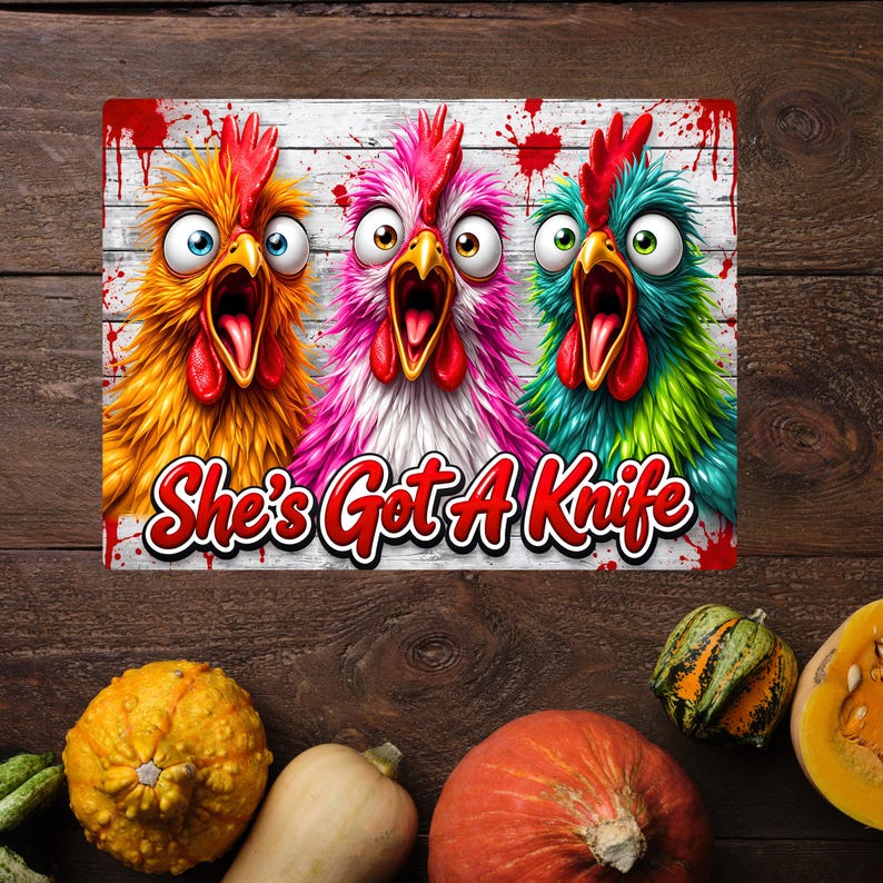 Puede incluir: Un letrero rectangular con tres pollos de dibujos animados con ojos muy abiertos y picos abiertos sobre un fondo de tablones de madera blanca con salpicaduras de pintura roja. El texto "She's Got A Knife" aparece en letras rojas.