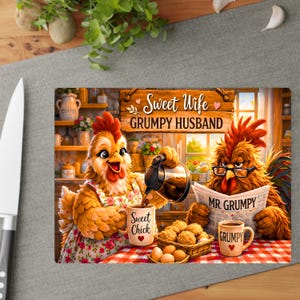 Peut inclure: Une planche &agrave; d&eacute;couper rectangulaire illustr&eacute;e de deux poulets dans une cuisine. L'un porte un tablier &agrave; fleurs et verse du caf&eacute; dans une tasse marqu&eacute;e Sweet Chick. L'autre porte des lunettes et lit un journal intitul&eacute; MR. GRUMPY.