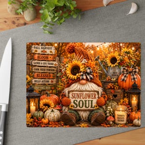 May include: A rectangular glass cutting board featuring a gnome wearing a burnt orange hat with a sunflower, holding a sign that reads Sunflower Soul. The scene includes pumpkins, sunflowers, lanterns, and a signpost with fall-themed text.