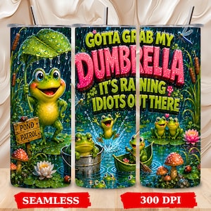 May include: A cylindrical tumbler featuring a vibrant pond scene with green frogs, water lilies, mushrooms, and a wooden sign labeled Pond Patrol. The text reads Gotta Grab My Dumbrella It's Raining Idiots Out There in bold pink and green letters.
