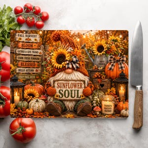May include: A rectangular glass cutting board featuring a gnome wearing an orange hat with sunflowers, holding a sign that reads SUNFLOWER SOUL. The design includes pumpkins, lanterns, a watering can, and a wooden sign with autumn-themed text.