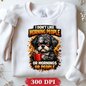 May include: A white crewneck sweatshirt featuring a graphic of a grumpy black and white dog holding a red coffee mug. The text reads I DON'T LIKE MORNING PEOPLE OR MORNINGS OR PEOPLE in black and orange lettering against a paint splatter background.