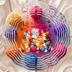 May include: A circular metal wind spinner featuring a colorful illustration of five kittens playing with various balls of yarn. The text "Life is Better with Cats" is printed in black script above the kittens, surrounded by small black paw prints.