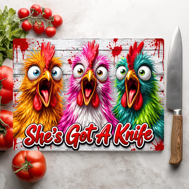 Puede incluir: Una tabla de cortar rectangular con un gr&aacute;fico de tres pollos de ojos muy abiertos y gritando en colores amarillo, rosa y verde azulado sobre un fondo de madera blanca con salpicaduras rojas y el texto She's Got A Knife en letras rojas.