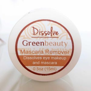 May include: A white container with a brown label featuring the text "Dissolve Greenbeauty Mascara Remover." The label also states that it dissolves eye makeup and mascara. The container is 0.5oz (15ml).