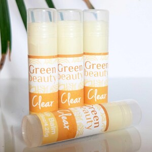 May include: Four clear lip balm tubes with yellow and white labels. The labels read "Green Beauty" and "Clear". One tube has the additional text "Lip Balm 15oz/4.25g".