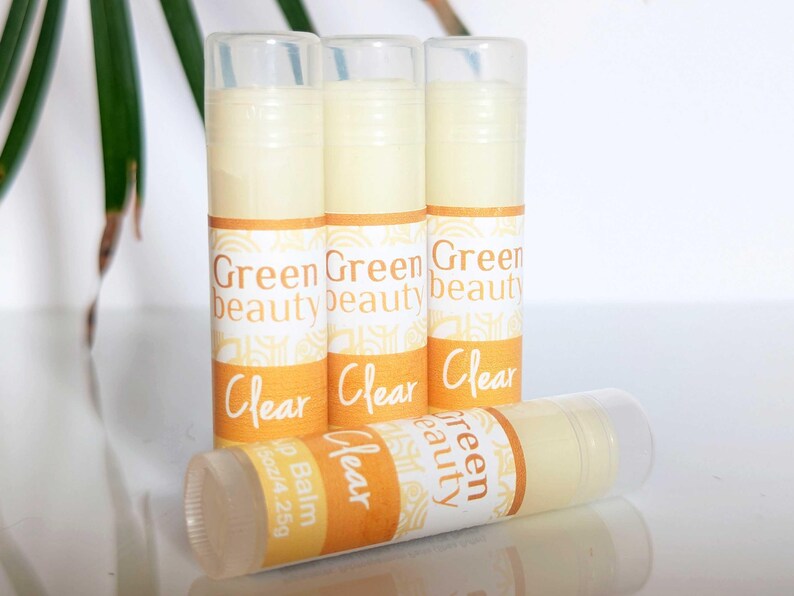 May include: Four clear lip balm tubes with yellow and white labels. The labels read "Green Beauty" and "Clear". One tube has the additional text "Lip Balm 15oz/4.25g".