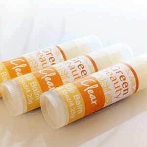 May include: Three clear lip balm tubes with yellow and white labels that read "Green Beauty Clear Lip Balm 1.5 oz/4.25g".