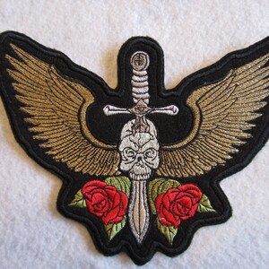 May include: Embroidered patch with a skull, sword, and two red roses. The sword is silver and has a black handle. The skull is white and has black eyes. The wings are gold and black.