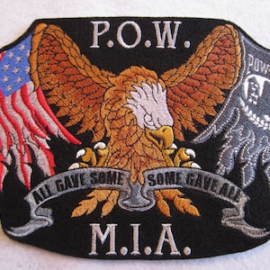 May include: A black embroidered patch with a bald eagle, an American flag, and a POW-MIA symbol. The eagle's wings are spread and it is holding a banner that reads "All Gave Some, Some Gave All". The patch also includes the text "P.O.W." and "M.I.A."