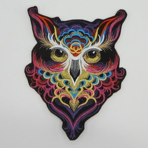 May include: A colorful embroidered owl patch with intricate details in shades of pink, blue, yellow, and gold. The owl's eyes are large and yellow, and the background is black.