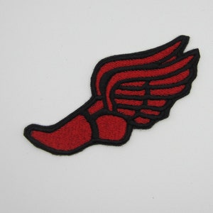 May include: Red and black embroidered patch of a winged foot, a common symbol for speed and athleticism.