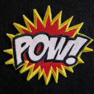 May include: A yellow and red embroidered patch with the word "POW!" in white letters with black outlines.
