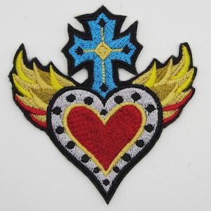 May include: Embroidered patch with a red heart with gold trim and wings, a blue cross with a yellow center, and a white and black dotted border.