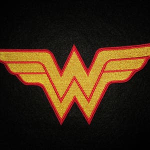 May include: A red and yellow embroidered Wonder Woman logo patch. The logo is a stylized 'W' with wings on either side.