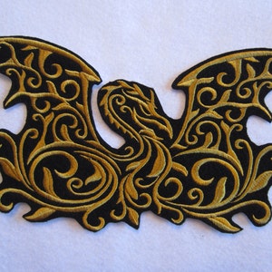 May include: A black embroidered patch with a gold dragon design. The dragon is surrounded by intricate floral patterns.